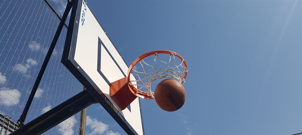 Balón de baloncesto entrando en la canasta de la pista del colegio